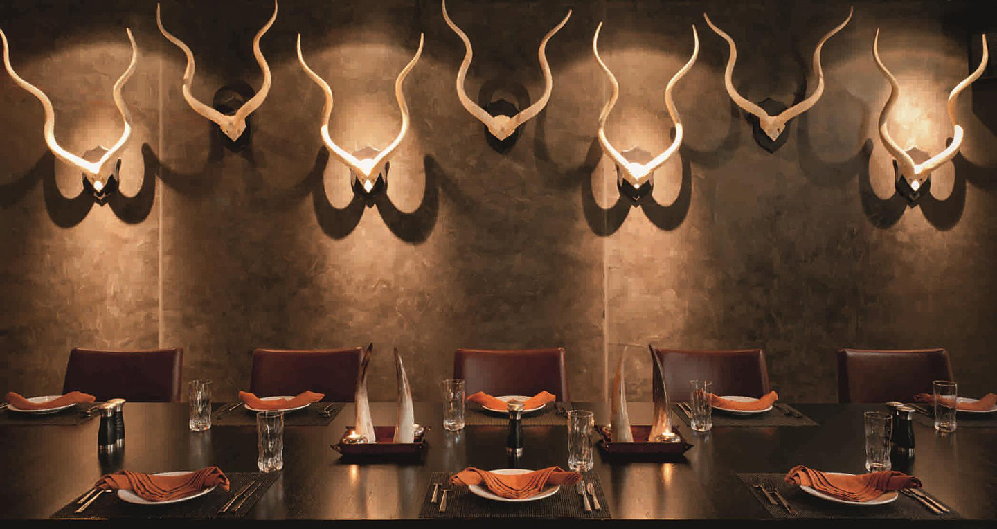 The chocolate coloured interior of Toro Toro Dubai with an exquisite table setting and creative bull horn motifs on the wall
